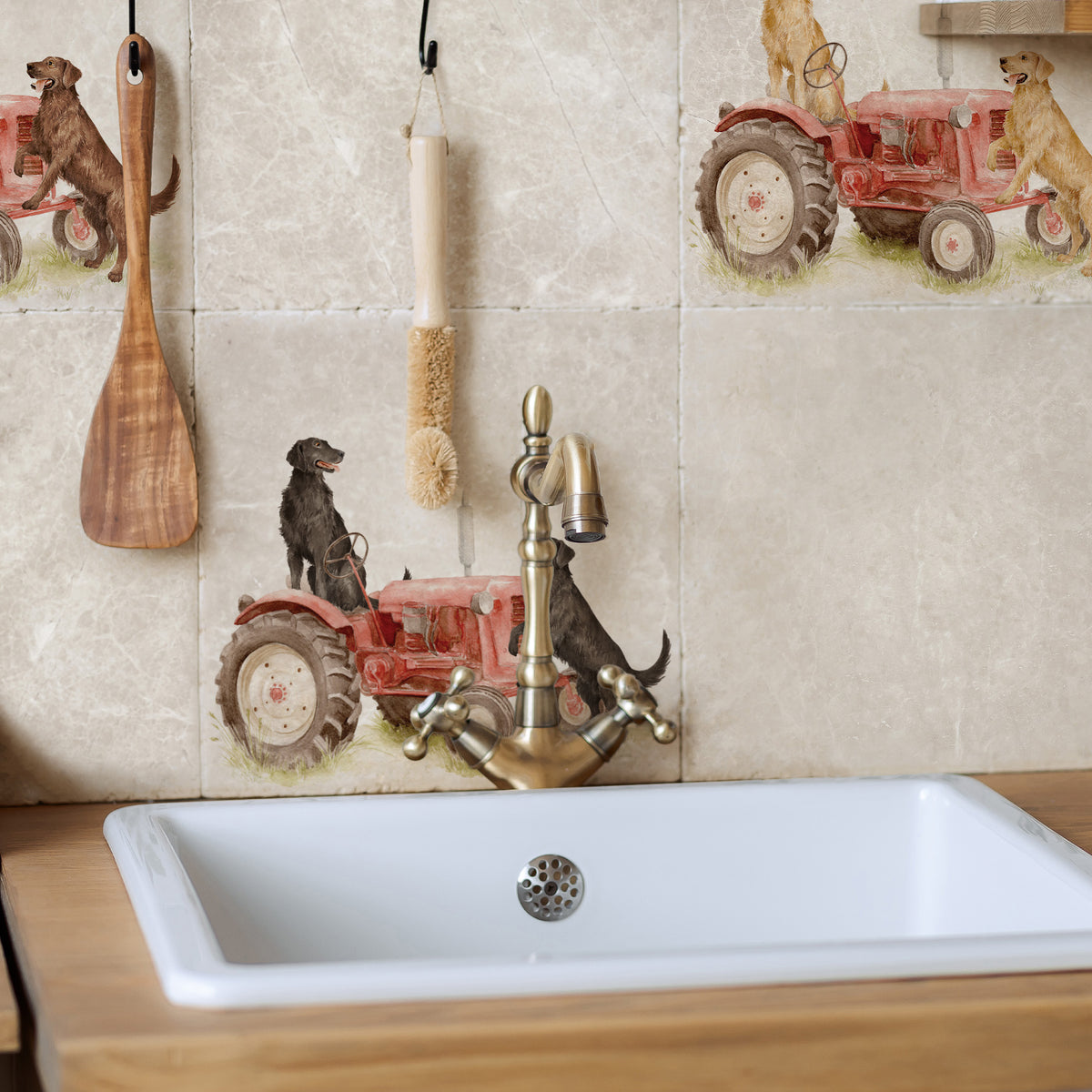 A kitchen backsplash featuring decorative beige stone tiles with printed red tractor and dog motifs, a white rectangular sink, and a brass faucet.