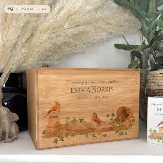 A beautifully crafted solid Bamboo wooden urn, personalised and finished with a soft watercolour design of Robins on a shelf sat on pots, when Robins appear a loved one is near. Thoughtfully made for either display or burial, this personalised urn can be customised to create a meaningful memorial. Perfect for holding ashes of a loved one or a beloved pet, it serves as a comforting tribute and keepsake. 