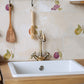 A country kitchen sink with a cream marble splash back made up of 20x40cm marble tiles featuring alternating watercolour fruits, including pears, apples, plums and grapes.