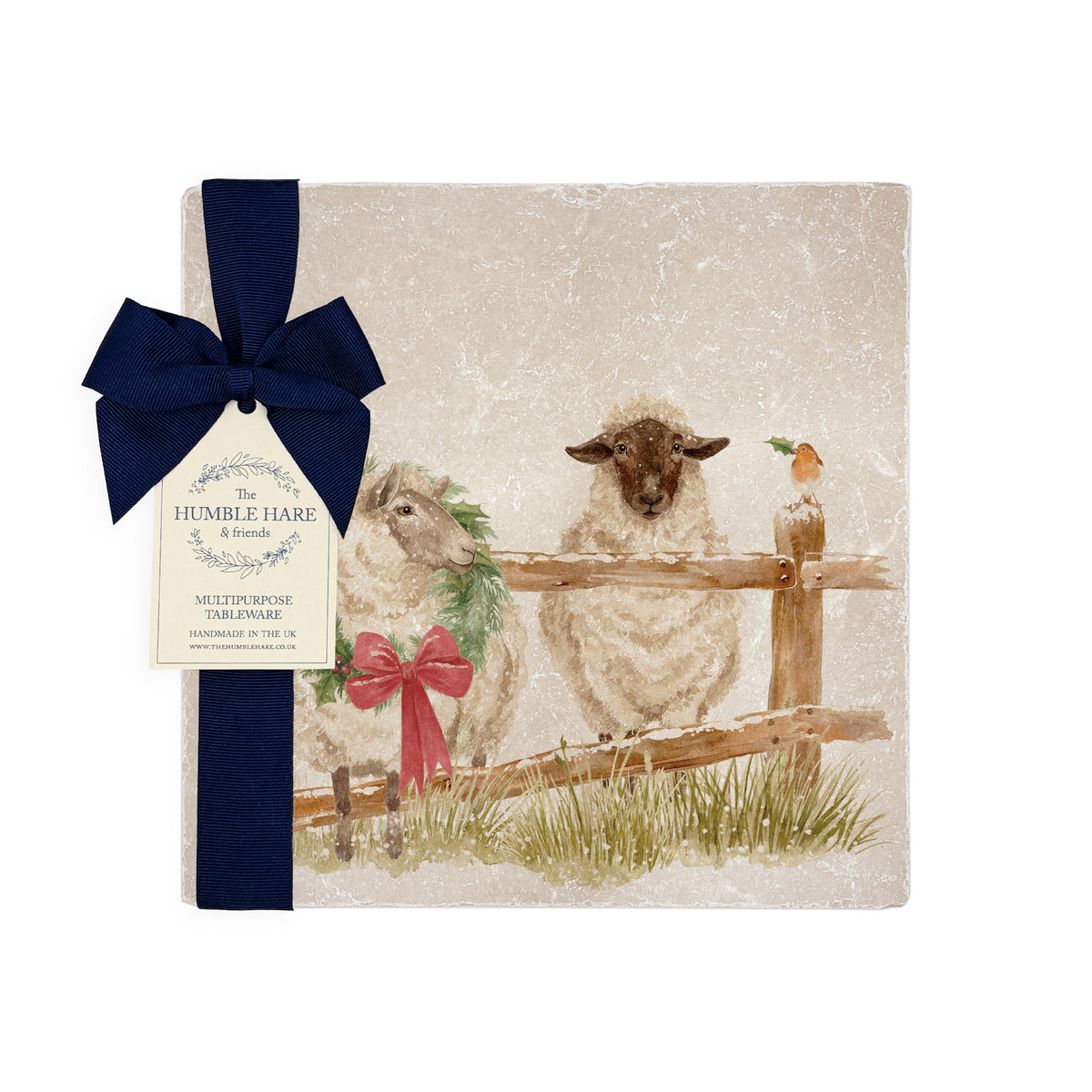 A medium marble platter featuring a watercolour illustration of sheep in the snow wearing a Christmas wreath. The platter is wrapped with a navy blue bow and paper tag.