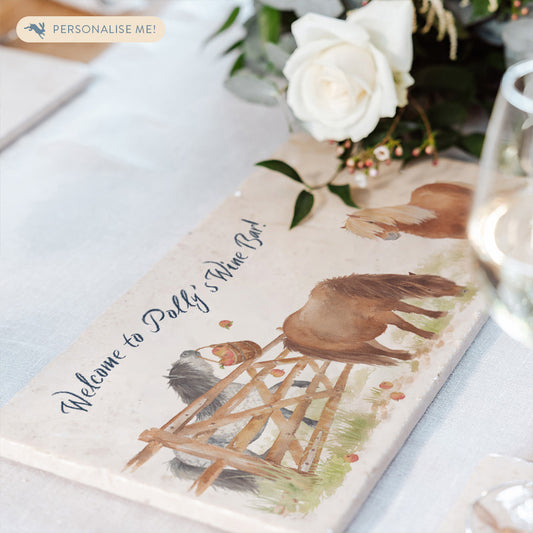 A marble sharing platter featuring a watercolour design of cheeky Shetland ponies, set on a table laid for dinner. The marble platter is personalised with dark blue text.