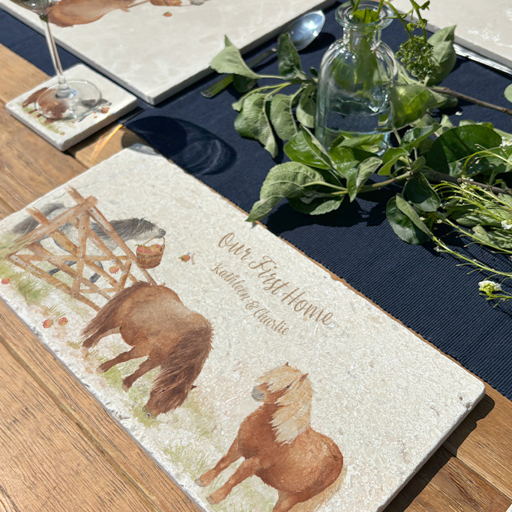 A marble sharing platter set on an outdoor table set for dinner. The platter has a cheeky Shetland pony design and has been personalised with a couple's names and the phrase 'Our First Home'.