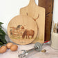 Round wooden chopping board on a kitchen worktop. The beech wood board features a watercolour design of cheeky Shetland ponies.