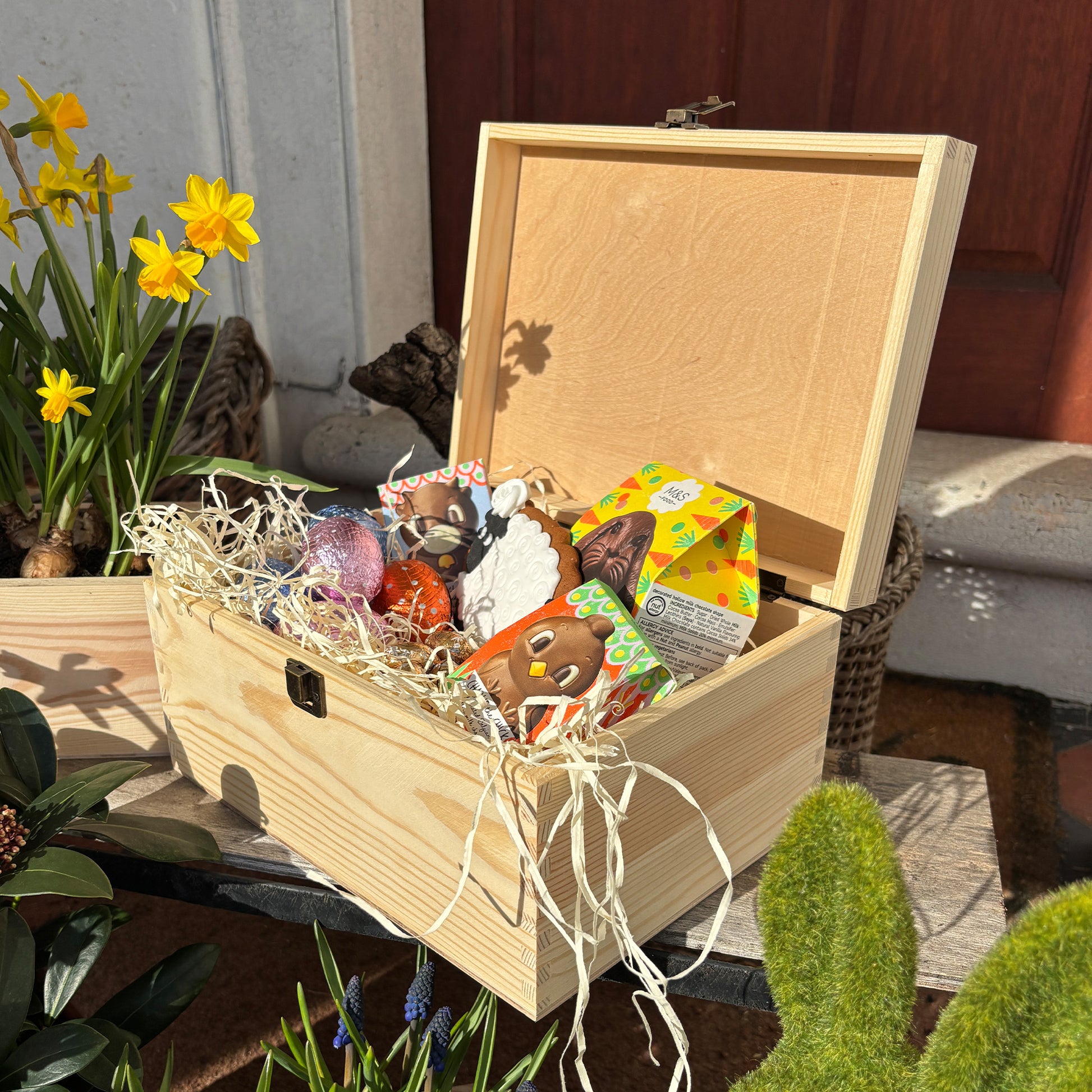 This wooden keepsake box is a large Easter box, perfect for creating a box full of Easter eggs and treats. The box is great for storing keepsakes in once the Easter treats have been eaten. This design has 3 chicks, the three chicks are looking at the pastel colour easter eggs on the floor  wondering if any more chicks may hatch or not. This gift box is full of easter chocolate treats 