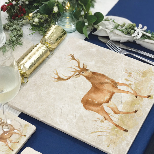 A handmade marble placemat featuring a noble stag in a watercolour style. The placemat is laid on a table set for Christmas dinner.