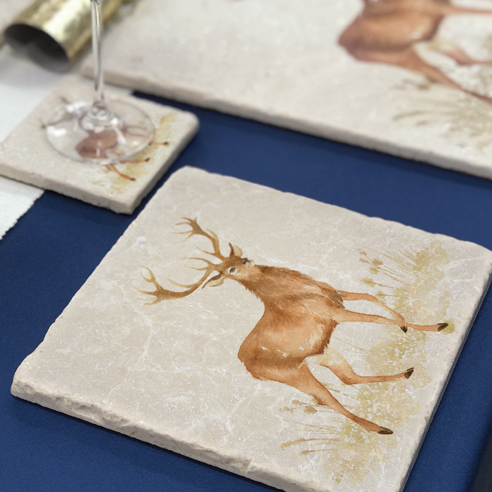 A handmade medium marble platter featuring a majestic stag in a watercolour style. The platter is set on a Christmas dinner table to be used as a side plate.