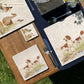A square medium marble platter featuring a watercolour design of two working spaniel dogs. The platter is set on a wooden table.