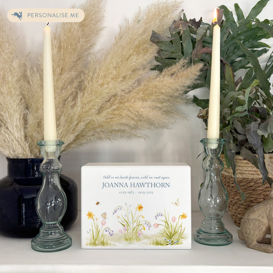 A beautifully crafted solid wooden urn, finished in white with a soft watercolour design with Spring flowers, Bees and Butterflies,. Thoughtfully made for either display or burial, this personalised urn can be customised to create a meaningful memorial. Perfect for holding ashes of a loved one or a beloved pet, it serves as a comforting tribute and keepsake.