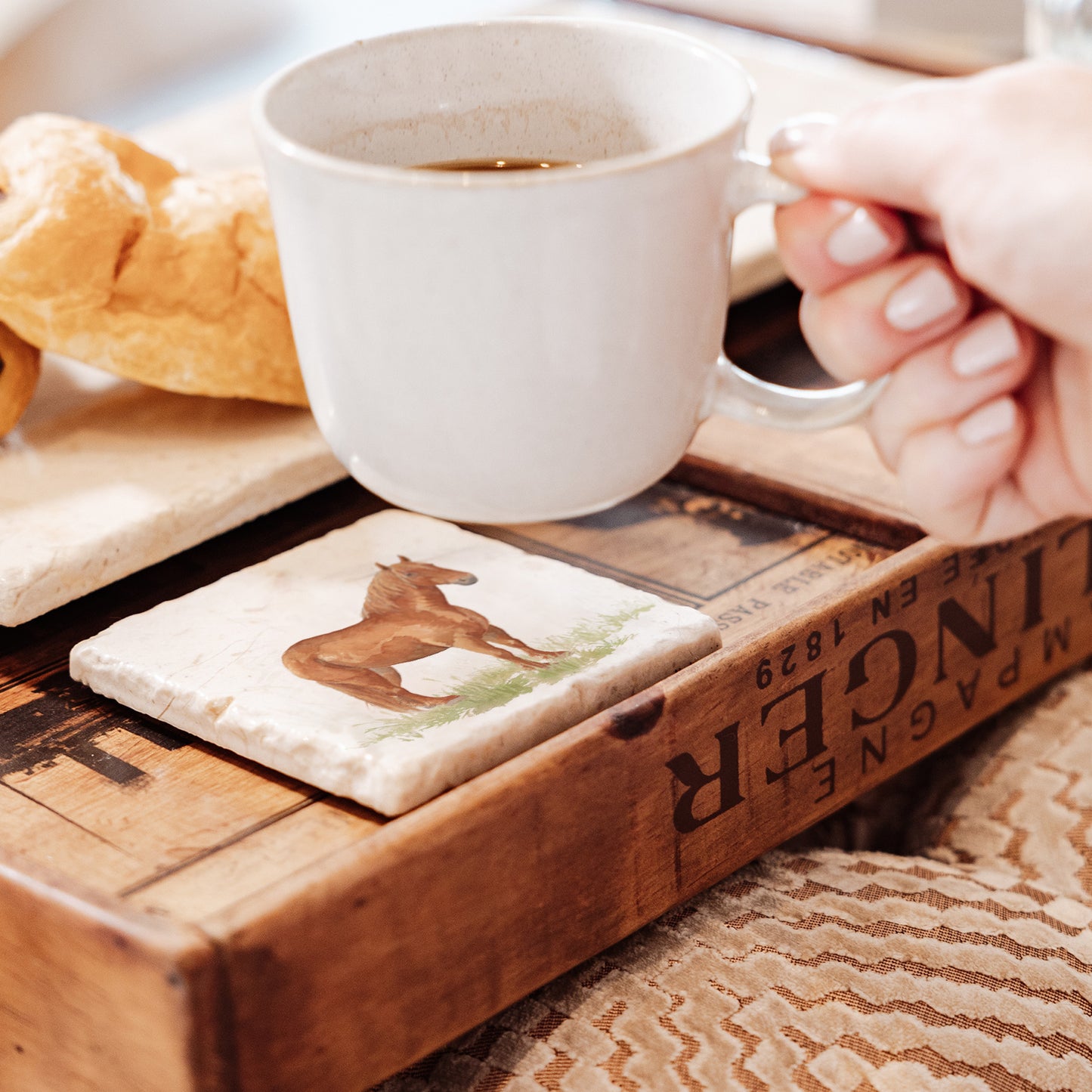 A square marble coaster on a tea tray, featuring a watercolour design featuring a watercolour design of a rare breed Suffolk Punch horse in a grassy field.