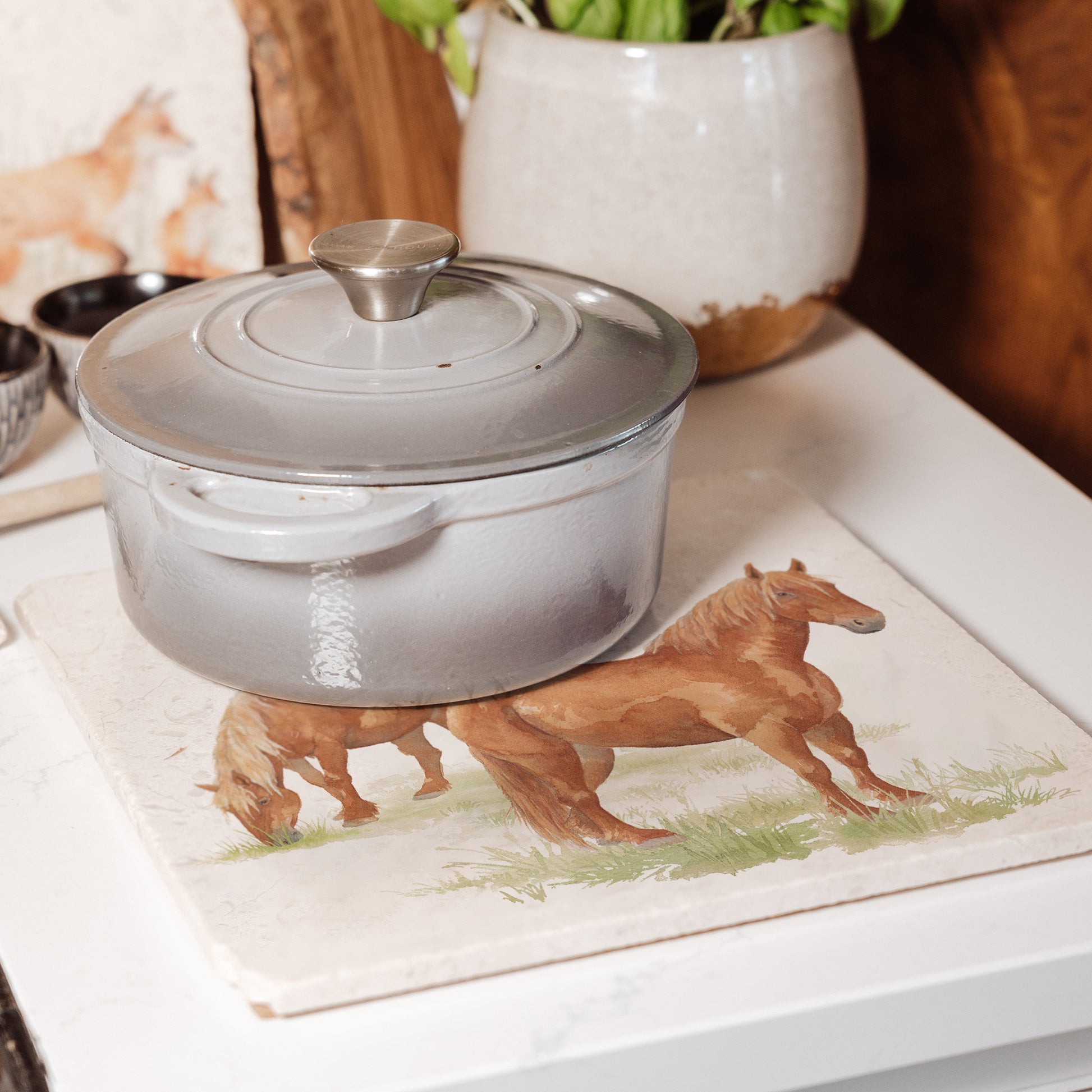 A large square multipurpose marble trivet, featuring a watercolour design of two Suffolk Punch horses in a field.