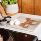 A large square multipurpose marble worktop saver, featuring a watercolour design of two Suffolk Punch horses in a field.