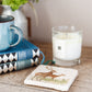 A marble coaster on a rustic wooden bedside table, the coaster features a watercolour design of a red deer stag and hind.