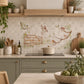 A decorative kitchen backsplash tile featuring a watercolour vintage-style illustration of birds perched on branches and a wooden fence, installed on a light grey tiled wall above a black stovetop in a styled kitchen setting.