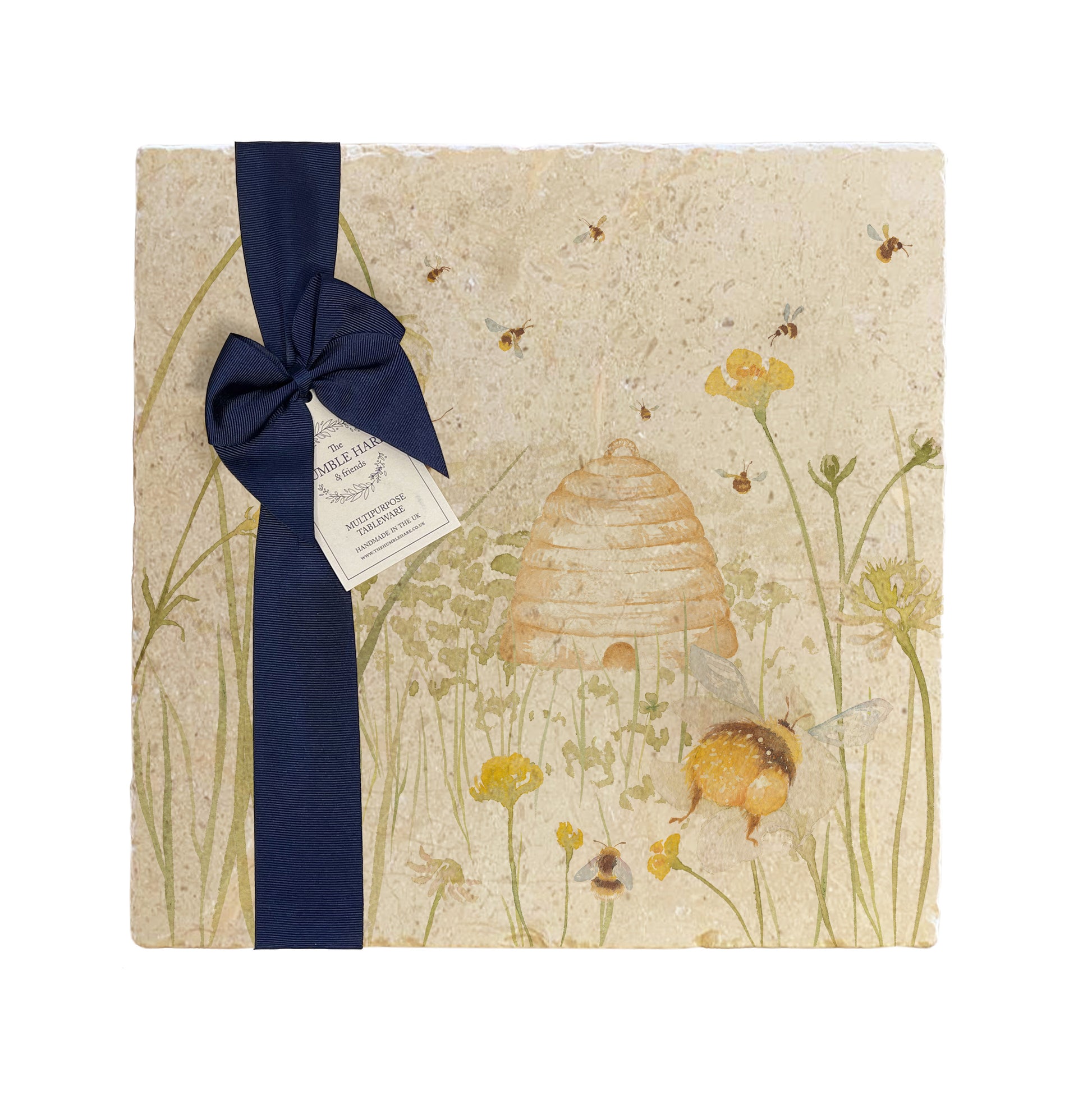 A multipurpose marble platter with a watercolour design featuring bees and a beehive in a buttercup meadow, packaged with a luxurious dark blue bow and branded gift tag.