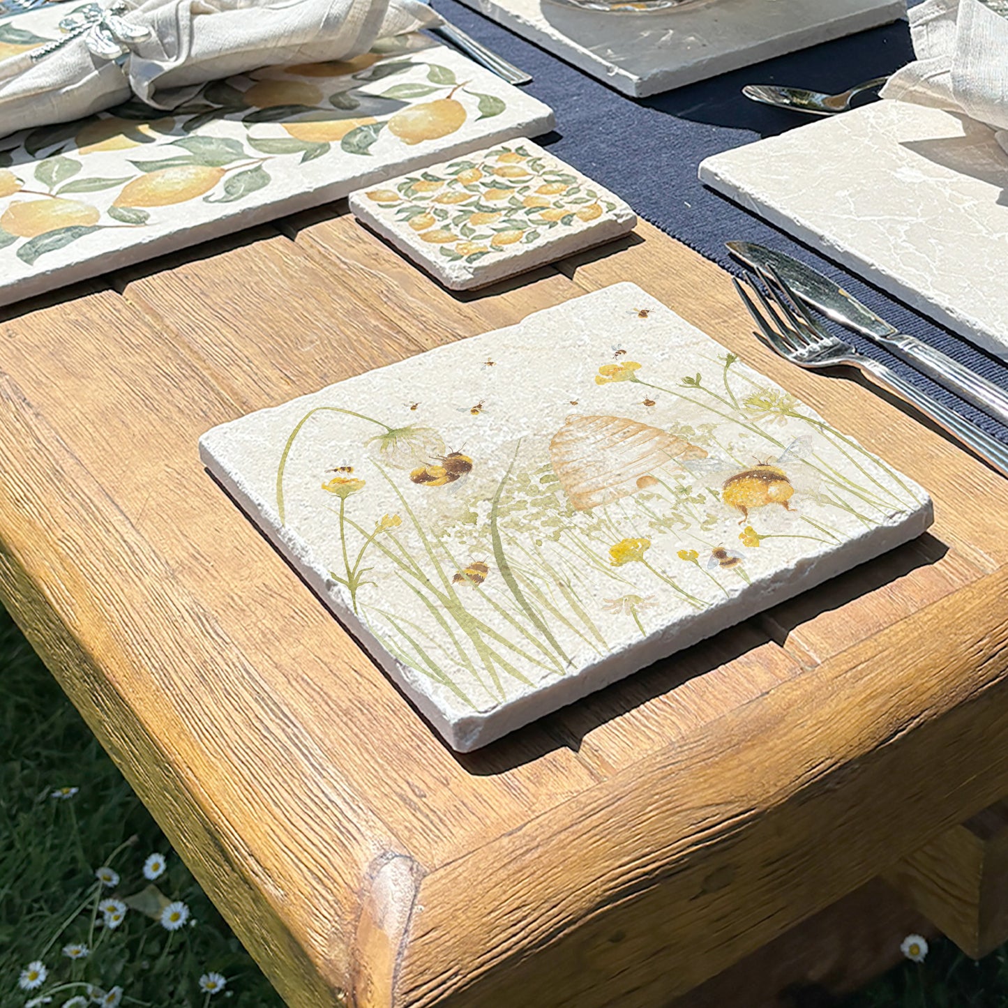 A medium marble platter with a bee and beehive design, the platter is being used as a teapot stand.