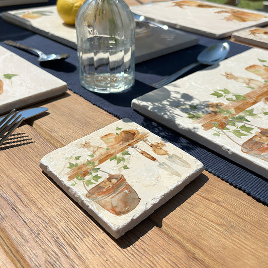 A marble coaster featuring a  watercolour design of mice in a garden shed among the flowerpots and tools.
