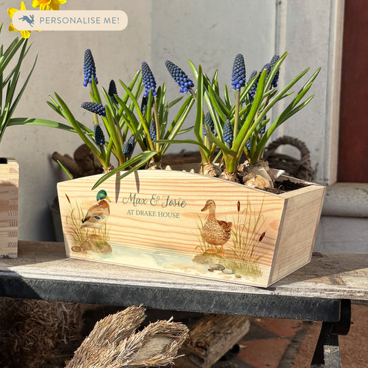An arched wooden planter box full of spring bulbs. The planter box shows a watercolour design of mallard ducks by the pond. The planter can be personalised with names and a selection of phrases to suit any occasion, including wedding, anniversary, engagement, birthday and new home.