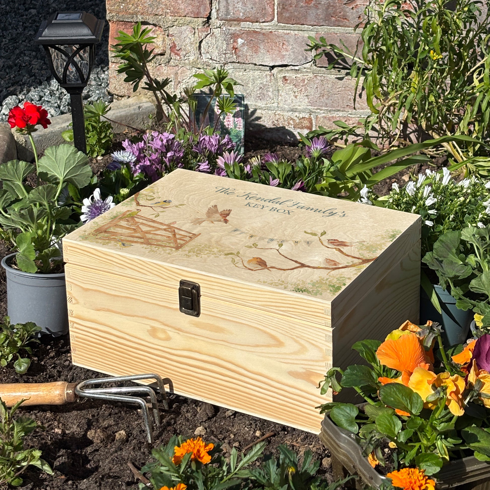 This medium sized wooden pine New home gift box can be filled with special gifts as a new home special occasion. The Design has a blue tit, robin, wren and sparrow on branches. There is a flying sparrow carrying a new home bunting. There is also a beautiful wooden gate opening to symbolise new beginnings with the gate opening. In the Garden new home gift.