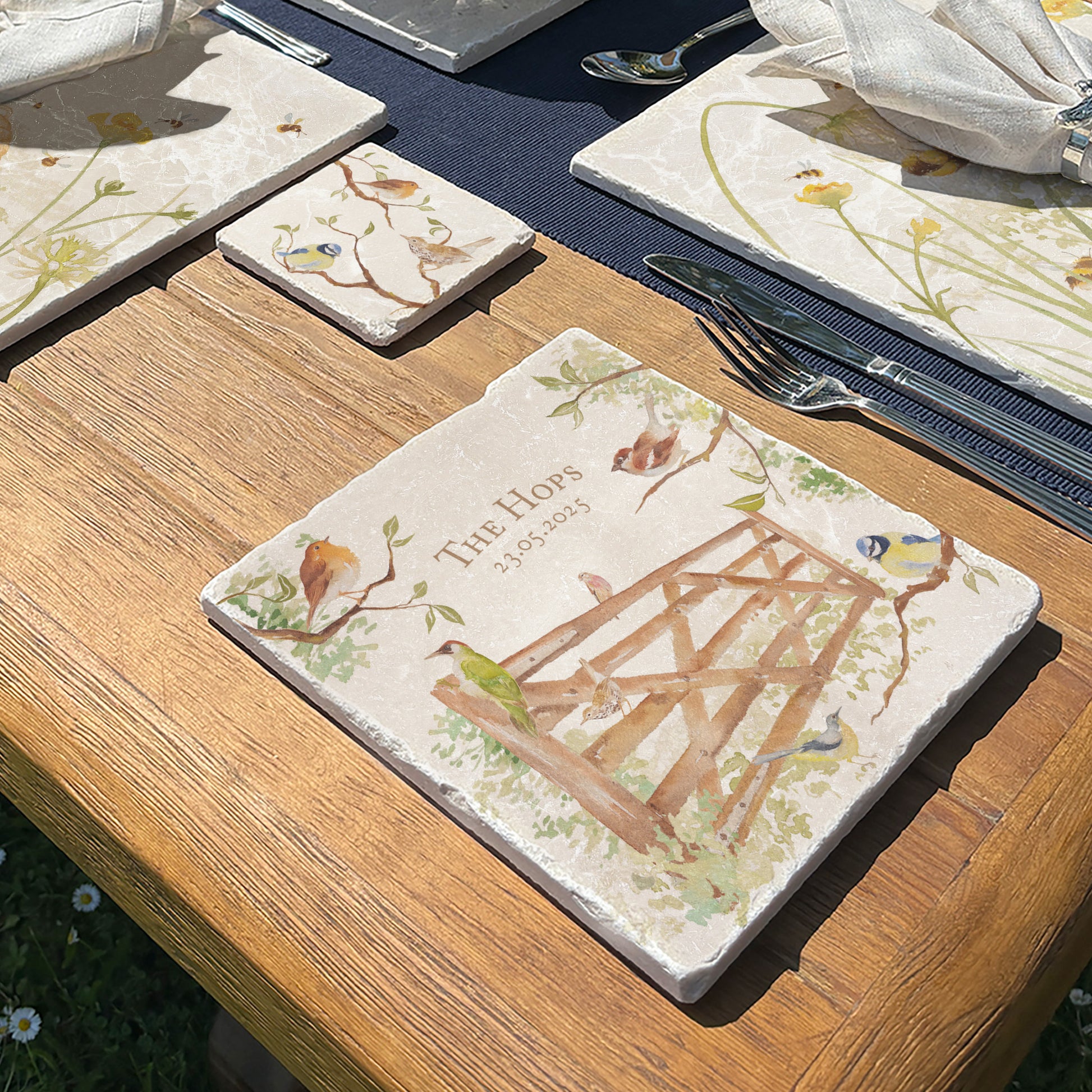 A wooden dining table set with a medium marble platter which is personalised with a special name or phrase, in The Humble Hares classic watercolour design featuring British garden birds in the hedgerow around the paddock gate.