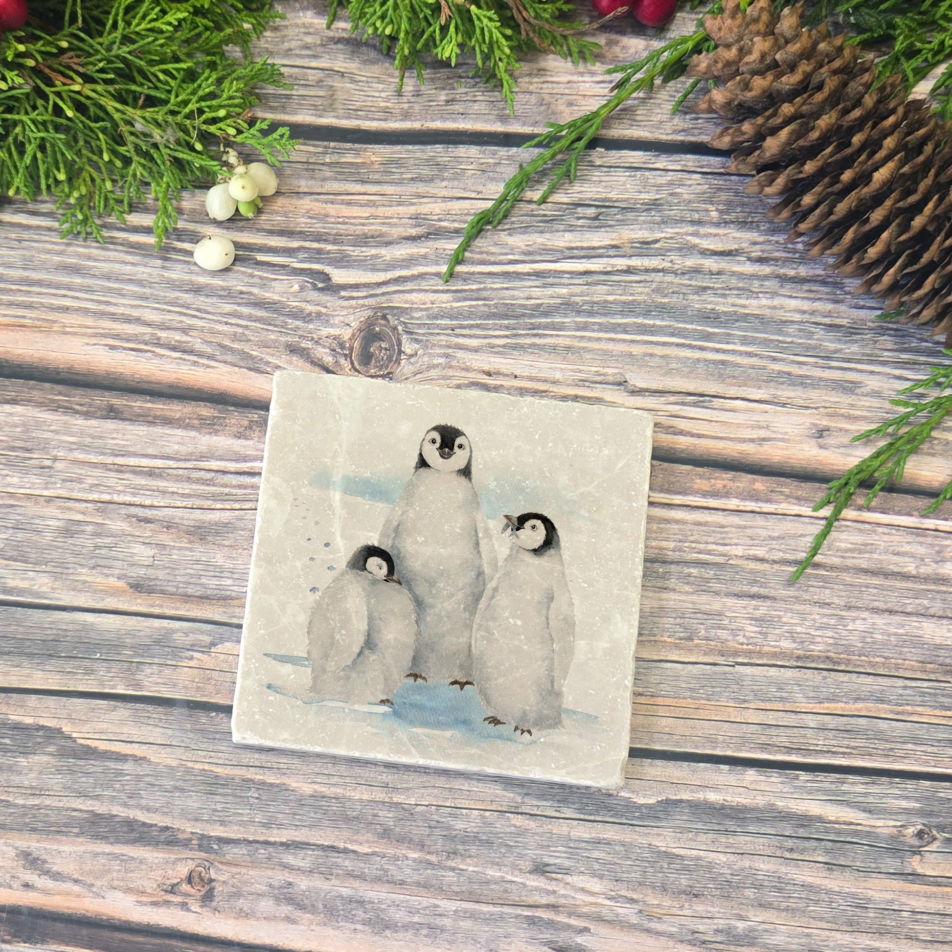 The Penguin Huddle Design features a set of 4 marble coasters with three penguins huddled together. One cheeky penguin has caught a fish to show his friends. 