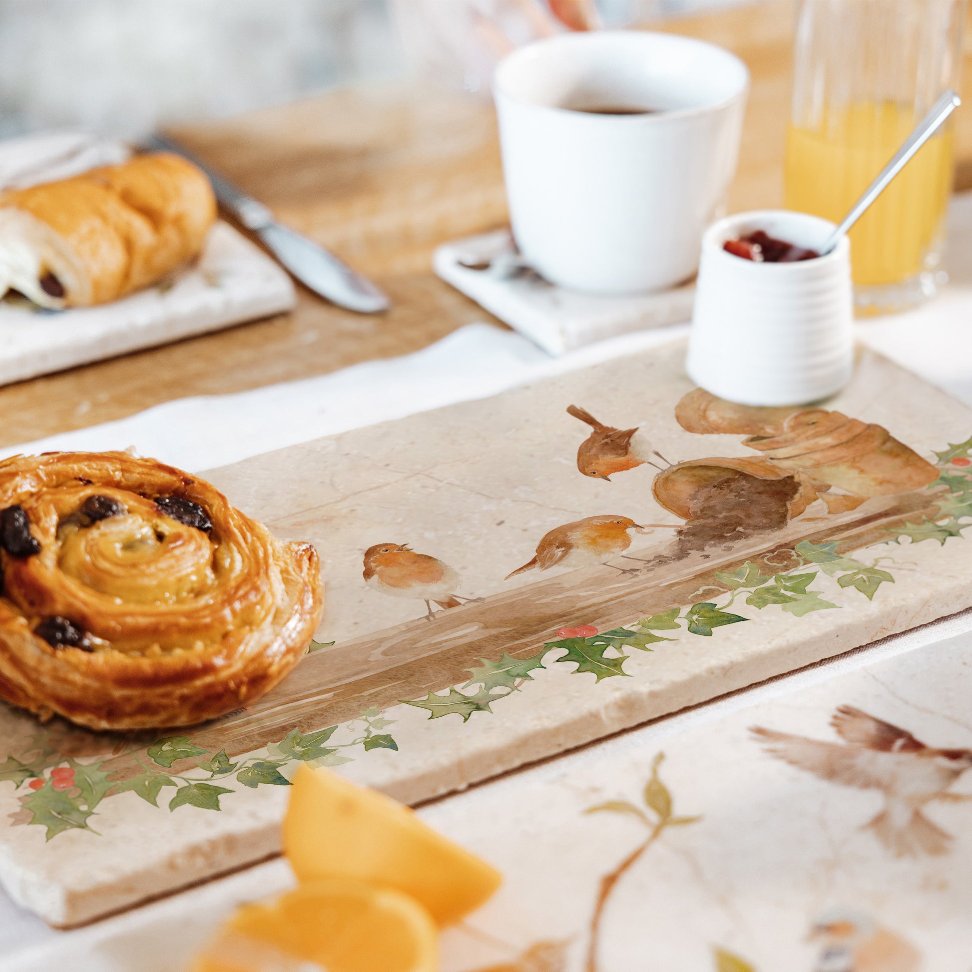 A multipurpose marble sharing platter with a Christmas robin design, the platter is being used as a table centrepiece to serve breakfast pastries.