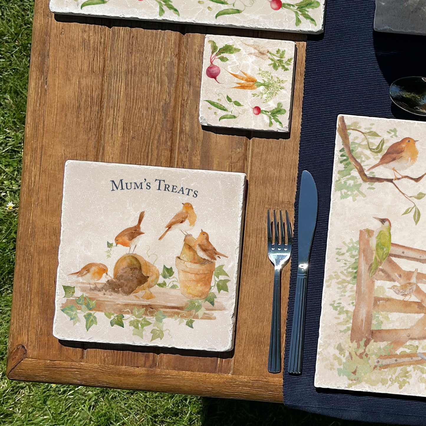 A medium square multipurpose marble platter, featuring a watercolour robin design. The platter is propped up on a kitchen worksurface ready to be used as a trivet, this also shows how you can personalise your platter.