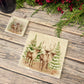 The Reindeers rest design features reindeer appearing from an opening in the wintery snowy forest. 