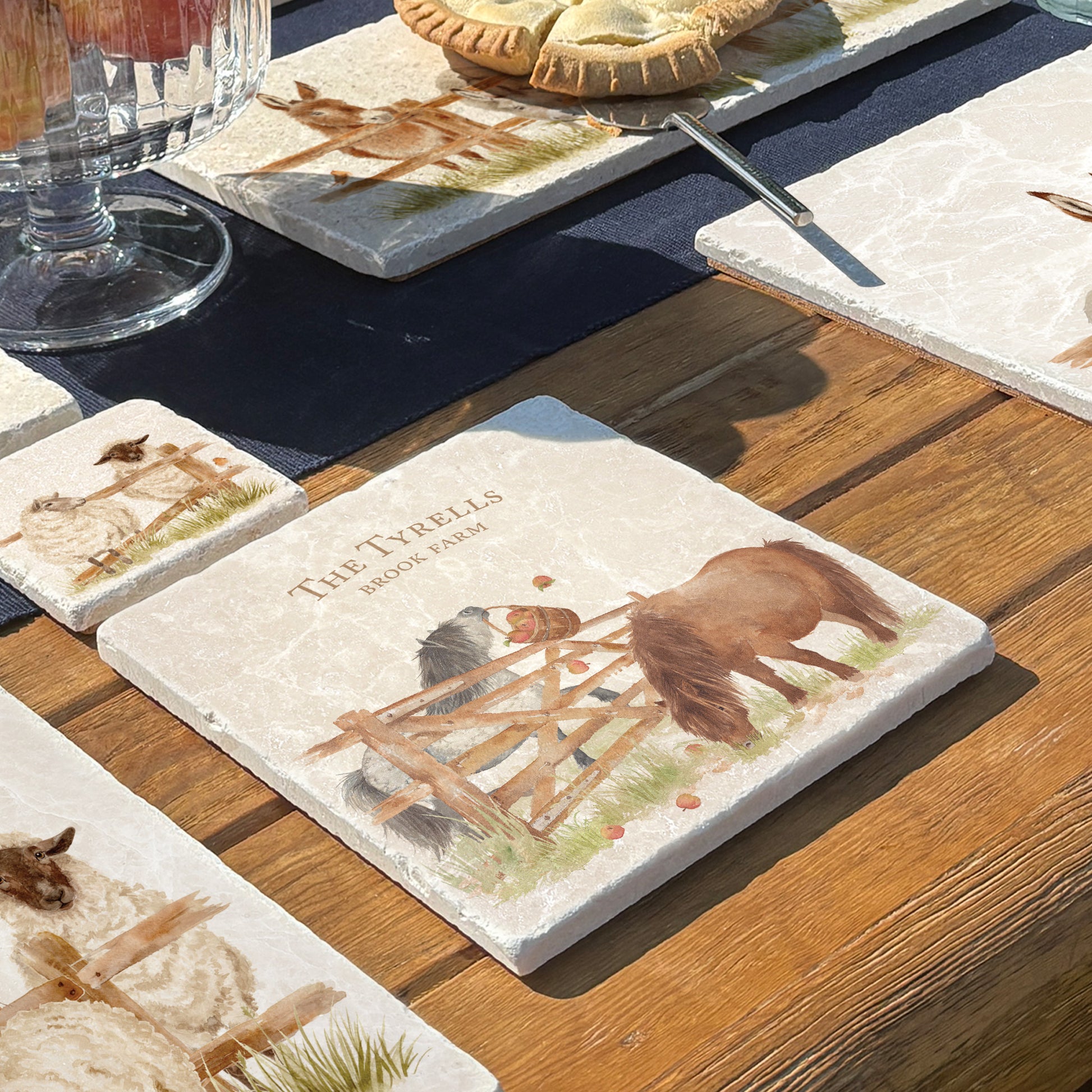 A medium personalised square multipurpose marble chopping board propped up on a country kitchen worksurface, featuring a watercolour design of two cheeky Shetland ponies stealing apples.
