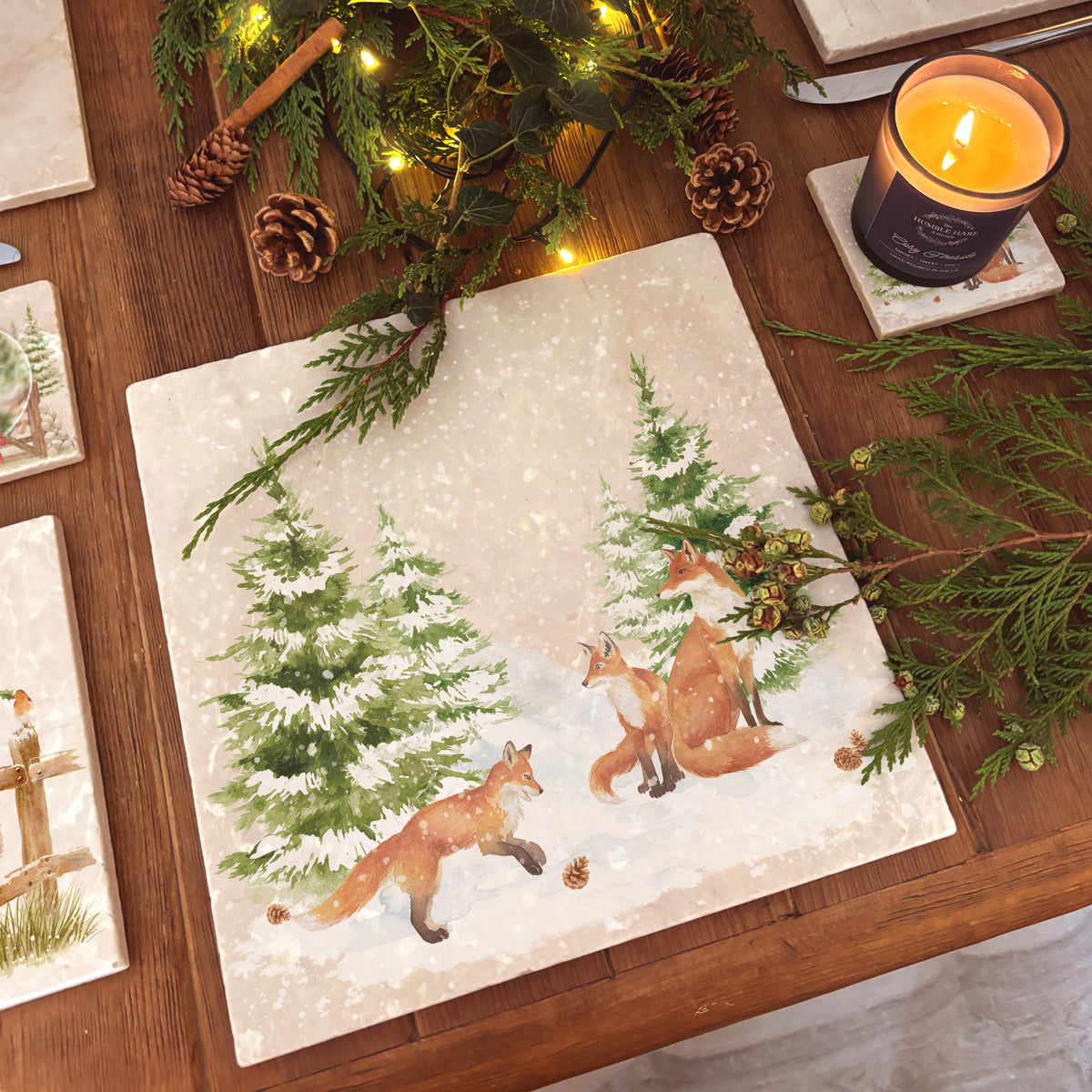A large square marble platter featuring a forest scene with a fox family playing in the snow.