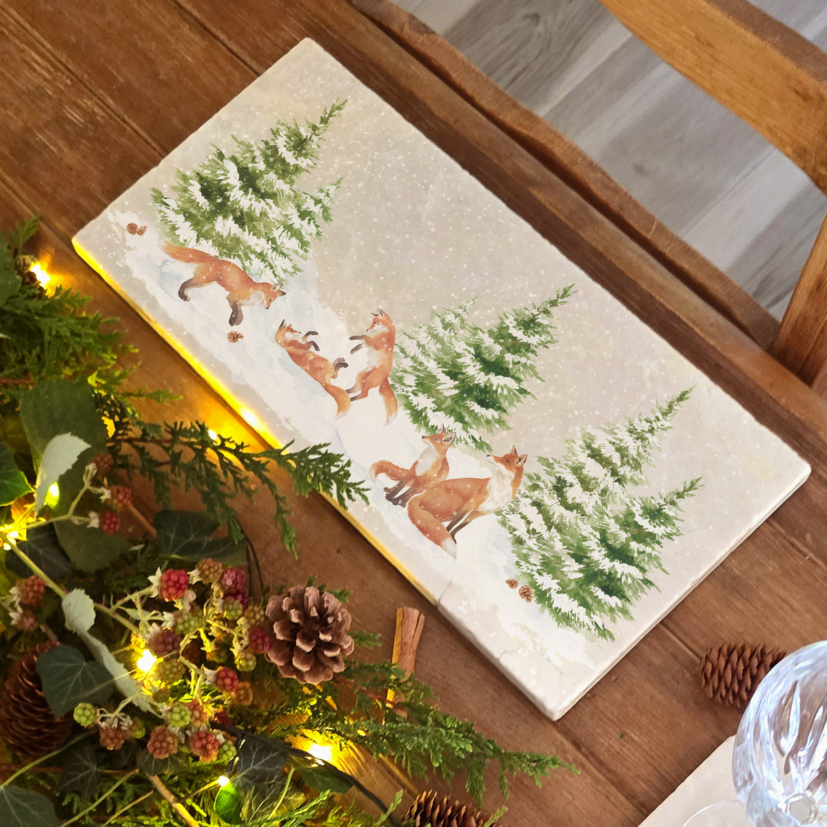 A rectangular marble sharing platter with a winter scene of a family of foxes and fox cubs playing in the snow.