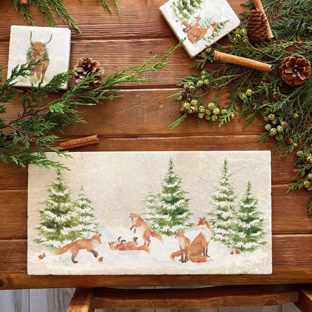 A rectangular marble sharing platter with a winter scene of a family of foxes and fox cubs playing in the snow.