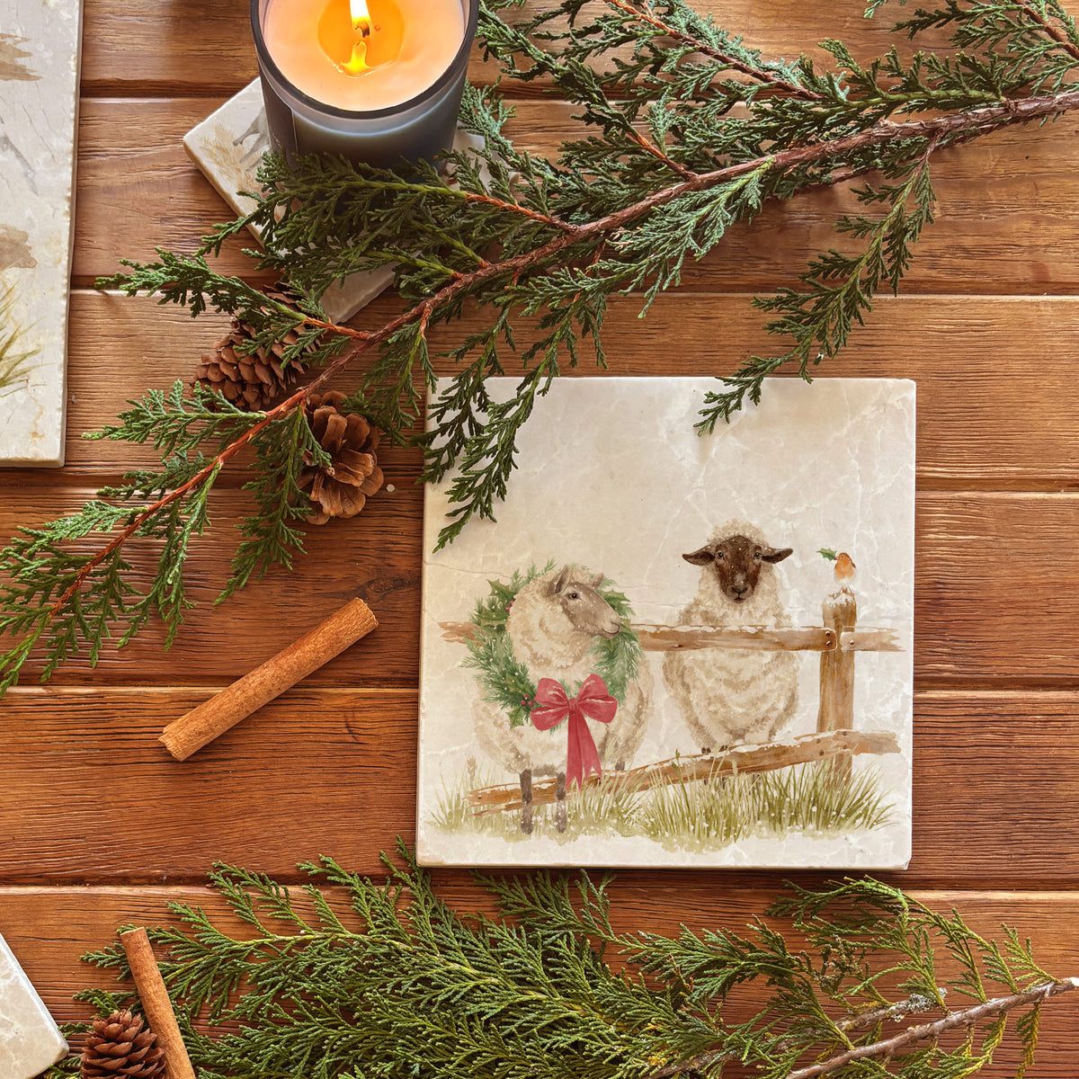 A medium marble platter featuring a watercolour illustration of a farmyard scene of sheep in the snow wearing a Christmas wreath.