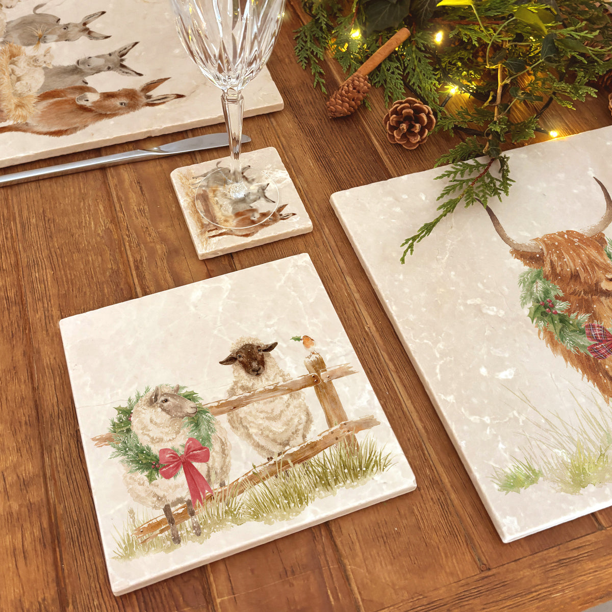 A medium marble platter featuring a watercolour illustration of a farmyard scene of sheep in the snow wearing a Christmas wreath.