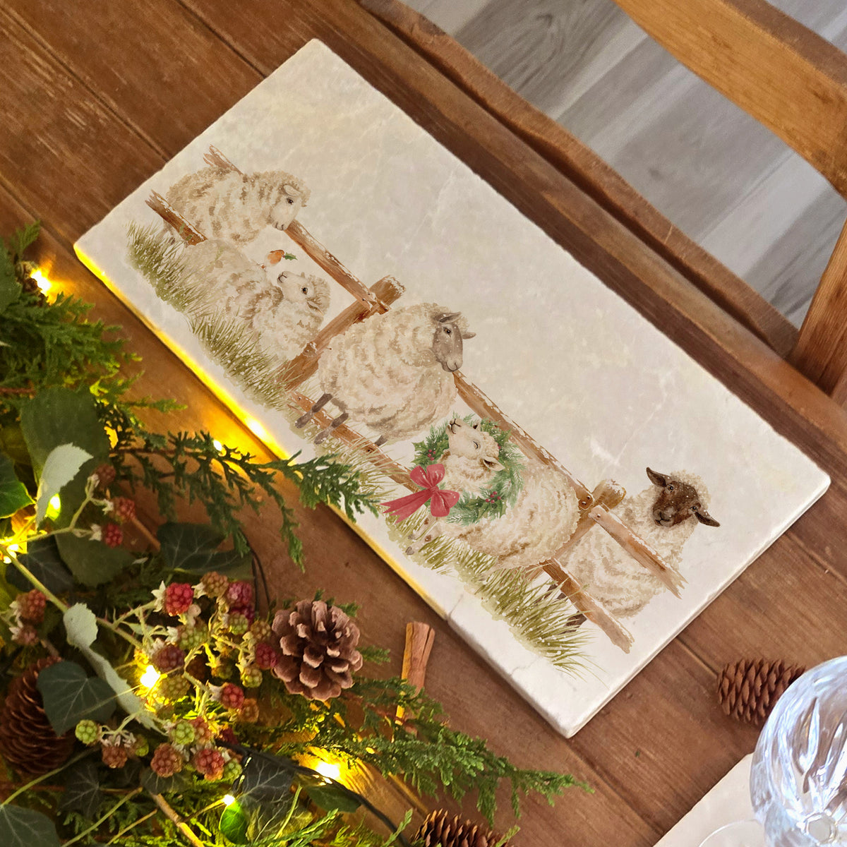 A rectangular marble sharing platter featuring a farmyard scene of sheep in the snow wearing a Christmas wreath.