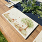 A handmade marble sharing platter featuring a watercolour scene of woodland animals under a willow tree. The platter is set on an al fresco dining table.