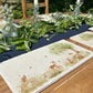 A handmade marble serving platter featuring a watercolour scene of woodland animals under a willow tree. The platter is set on an outdoor garden table.