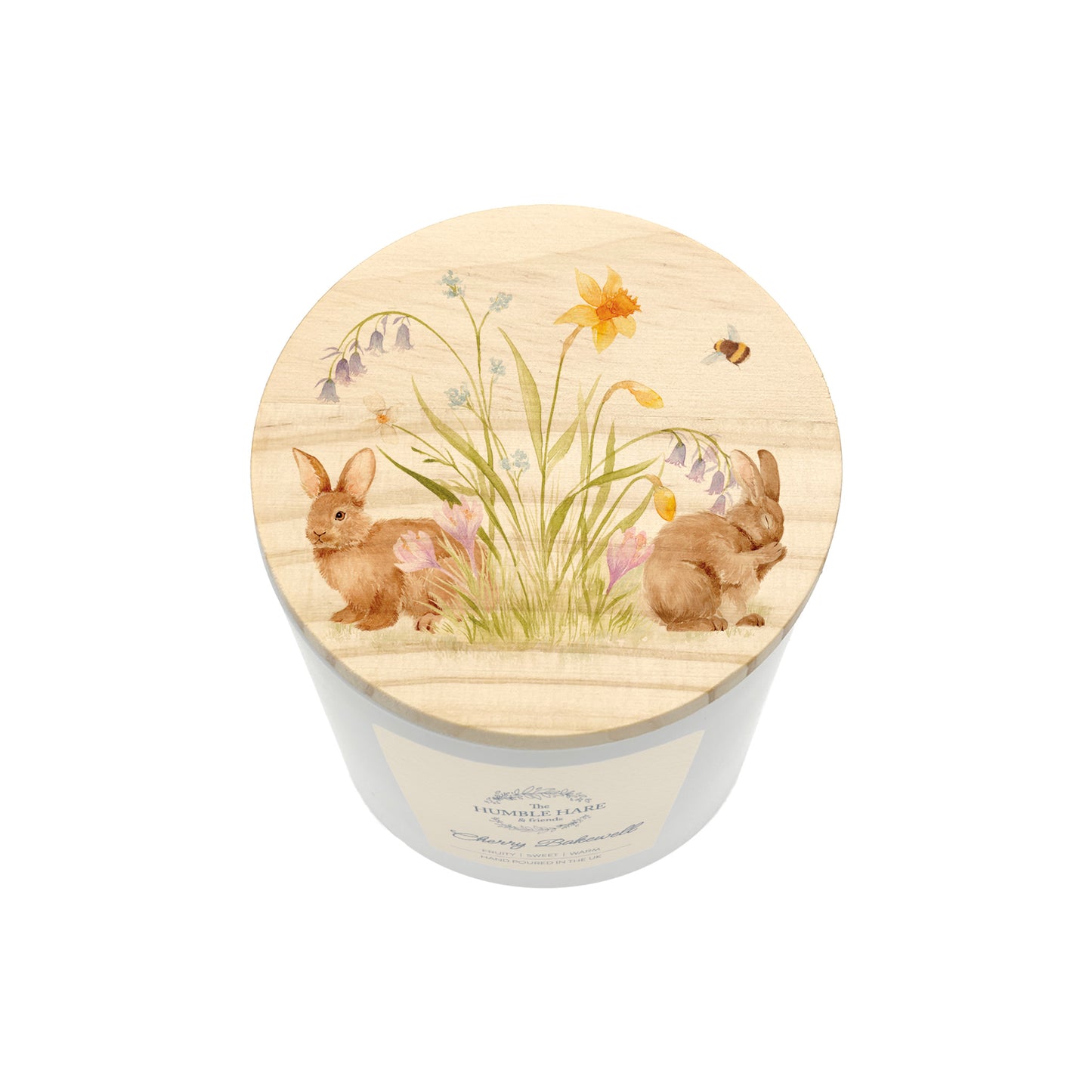A white glass candle jar with a light wood lid with an illustration bunnies surrounded by flowers and a bumblebee.