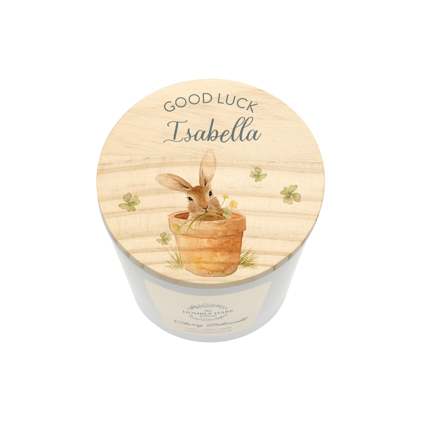 A personalised jar candle with a light wood lid featuring an illustration of a rabbit in a pot and the text 'GOOD LUCK Isabella'.