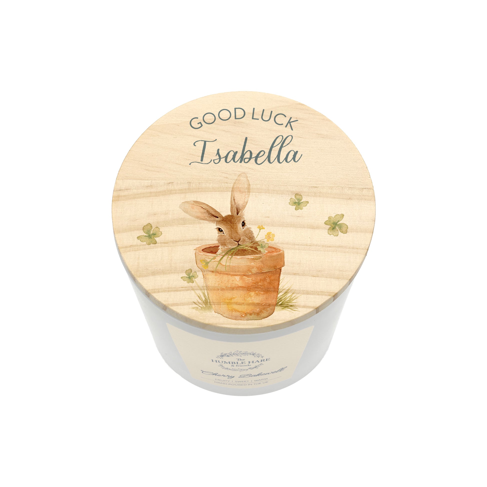 A personalised jar candle with a light wood lid featuring an illustration of a rabbit in a pot and the text 'GOOD LUCK Isabella'.