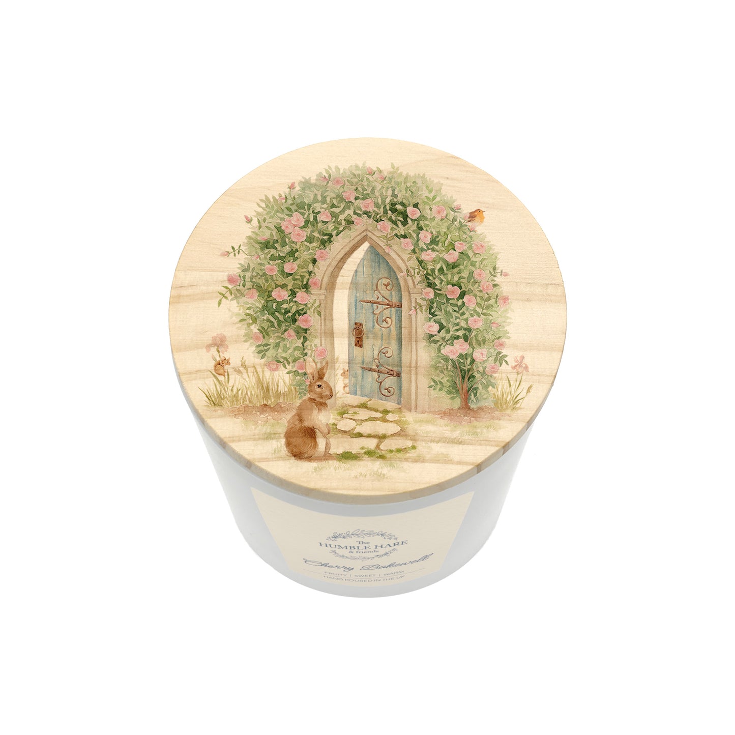 A white glass candle jar with a light wooden lid illustrated with a rose arch to a hidden garden with rabbits and wildlife hidden in the leaves. 