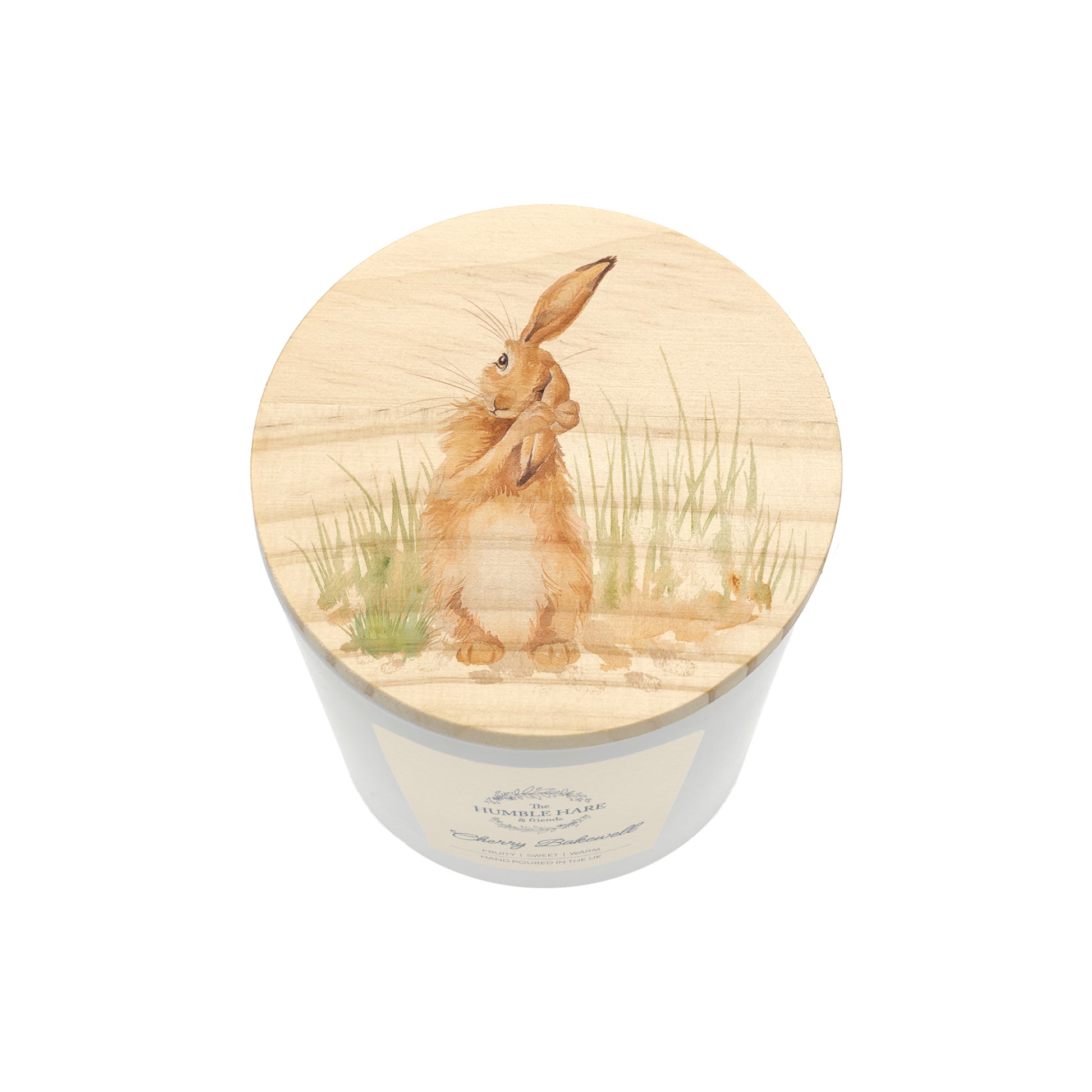 A white glass candle jar with a light wood lid with an illustration of a brown hare washing its ear in long grass.