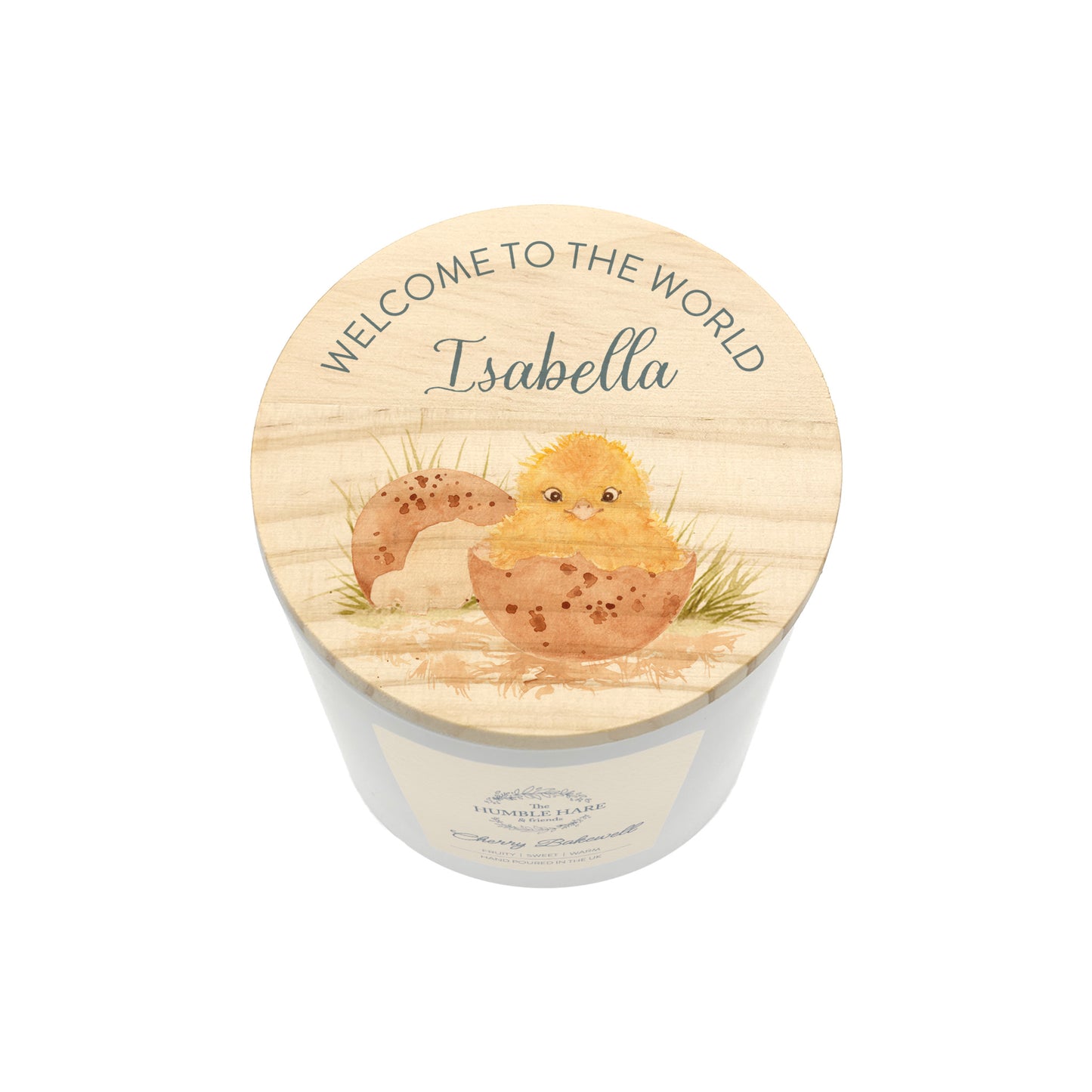 A personalised baby shower candle with a light wood lid featuring a watercolour illustration of a chick hatching from an egg and the text 'WELCOME TO THE WORLD Isabella'.
