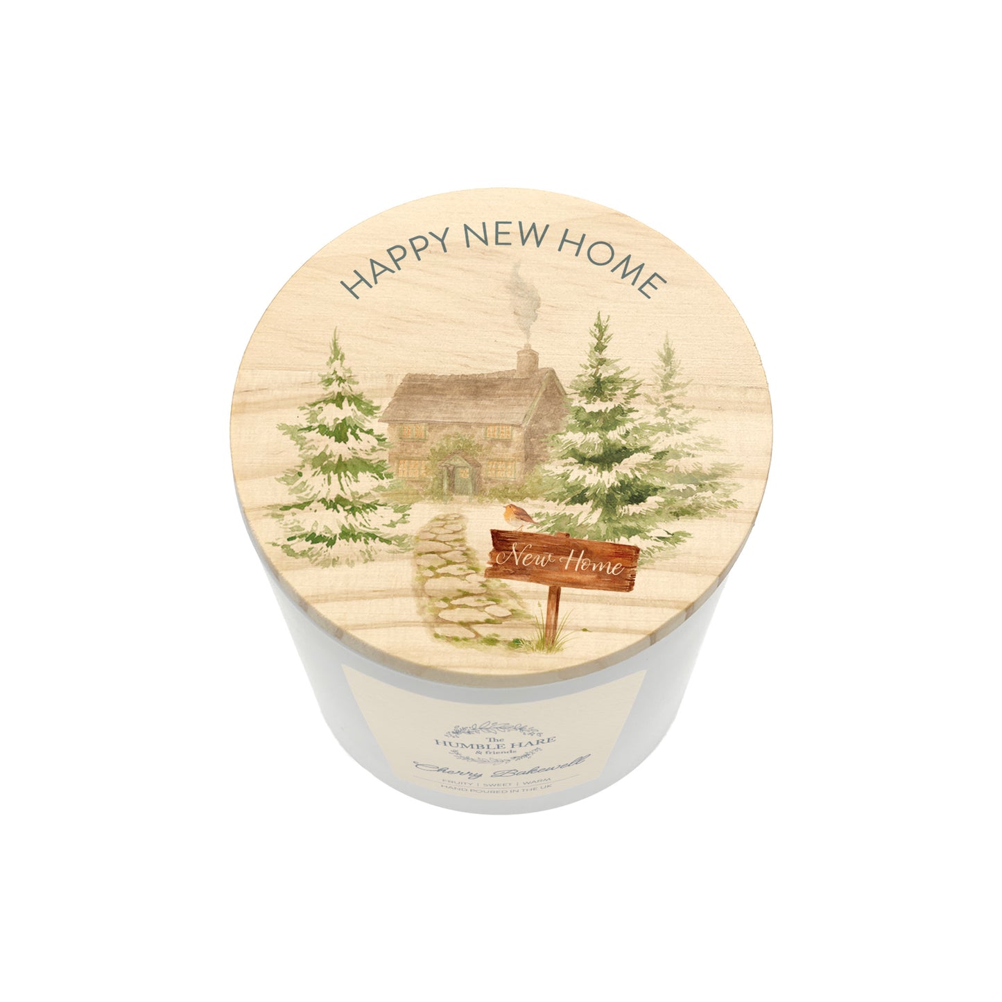 A white glass candle jar with a light wood lid with an illustration of a house in a forest and the words Happy New Home.