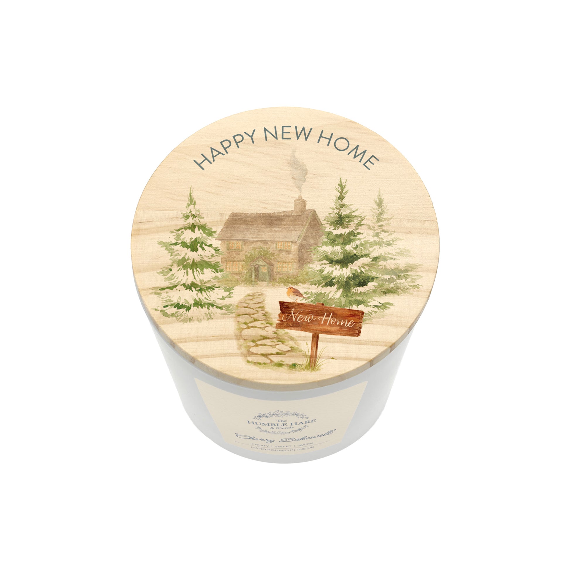 A white glass candle jar with a light wood lid with an illustration of a house in a forest and the words Happy New Home.