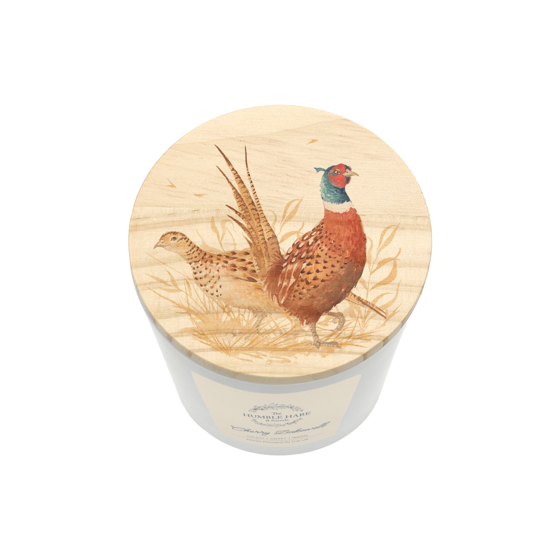 A candle in a white glass jar with a round light wood lid featuring a painted pheasant illustration, shown on a plain white background.