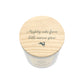 A white glass candle jar with a light wood lid with the quote 'Mighty oaks from little acorns grow' and a small leaping hare silhouette.