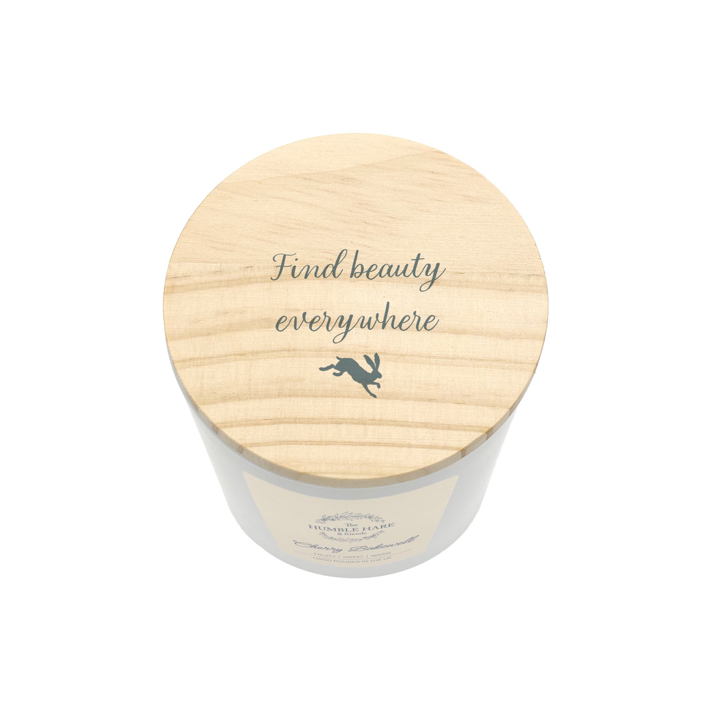 A white glass jar candle with a light natural wood lid with the phrase 'Find beauty everywhere' and a small leaping hare silhouette, shown on a plain white background.