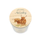 A personalised candle jar lid featuring a watercolour illustration of two Highland cows and the text 'MR & MRS McCarthy', set against a clean white background.