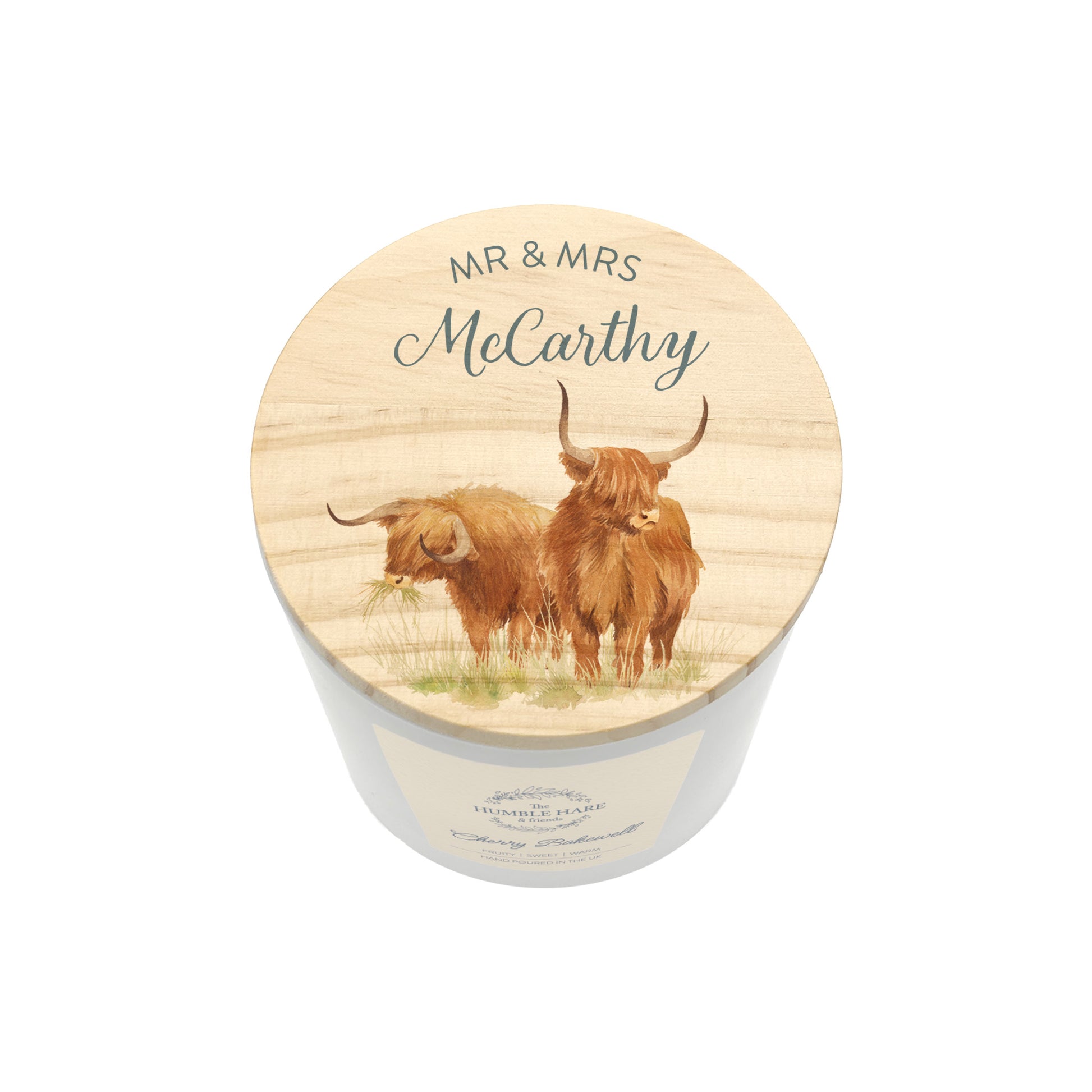 A personalised candle jar lid featuring a watercolour illustration of two Highland cows and the text 'MR & MRS McCarthy', set against a clean white background.