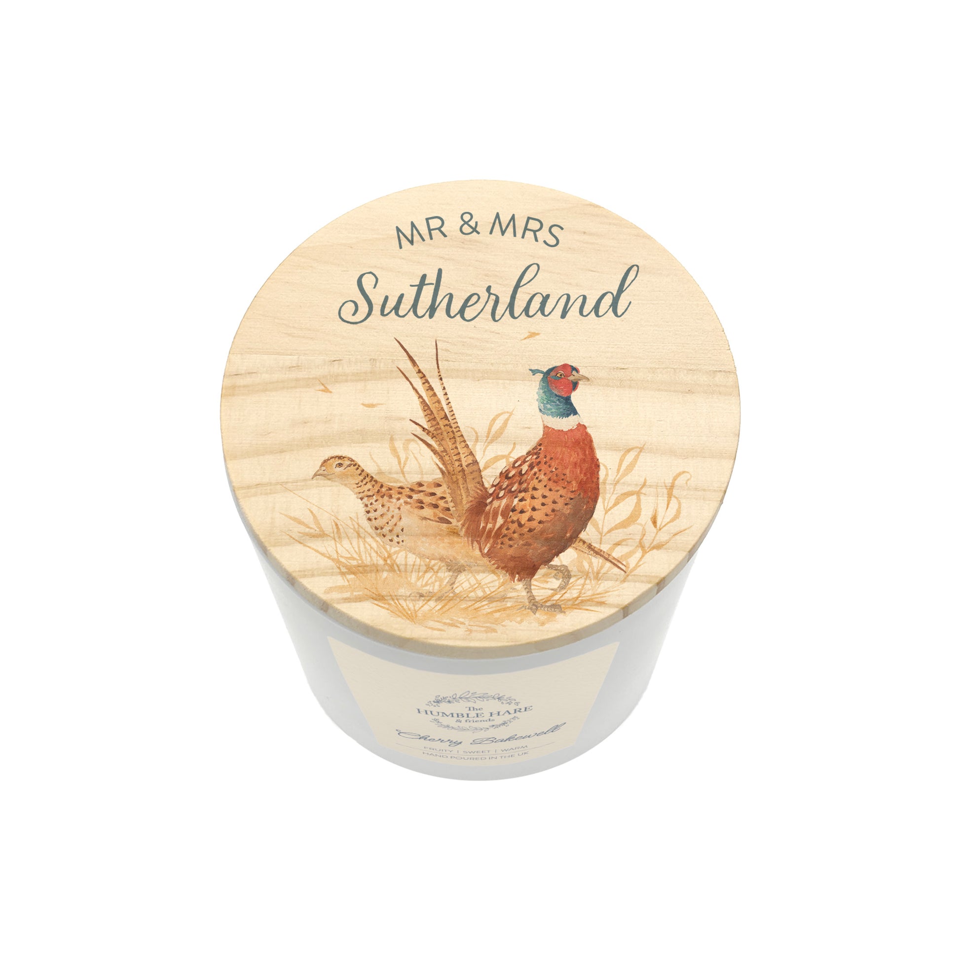 A personalised white glass candle jar with a light wood lid with an illustration of a male and female pheasant, and the text 'MR & MRS SUTHERLAND'.